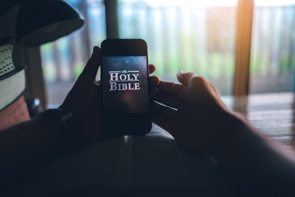 hand holding smart phone for read bible app. ready to study the Bible in the teachings of God Join us In Prayer